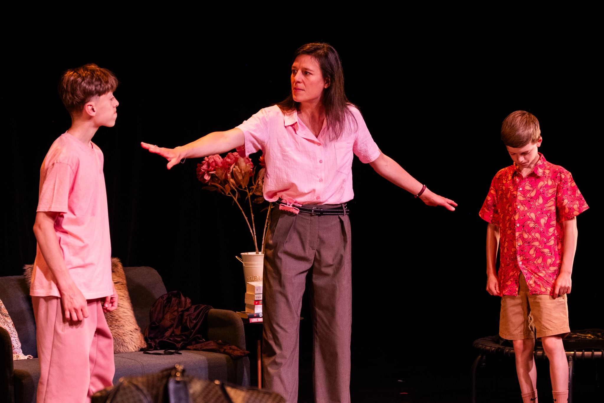 Célia Laguitton avec Gildas et Arthur Tronquoy sur scène, sous une lumière rose